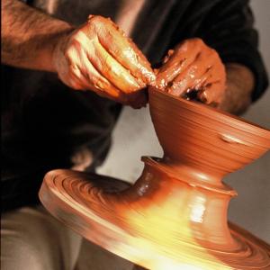 Manos creando pieza de barro en torno